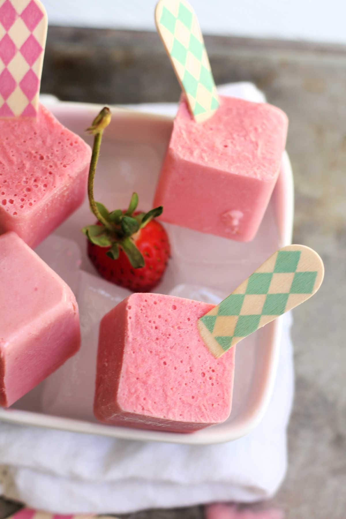 Creamy Strawberry Popsicles Over Ice With Fresh Strawberry In A White Bowl