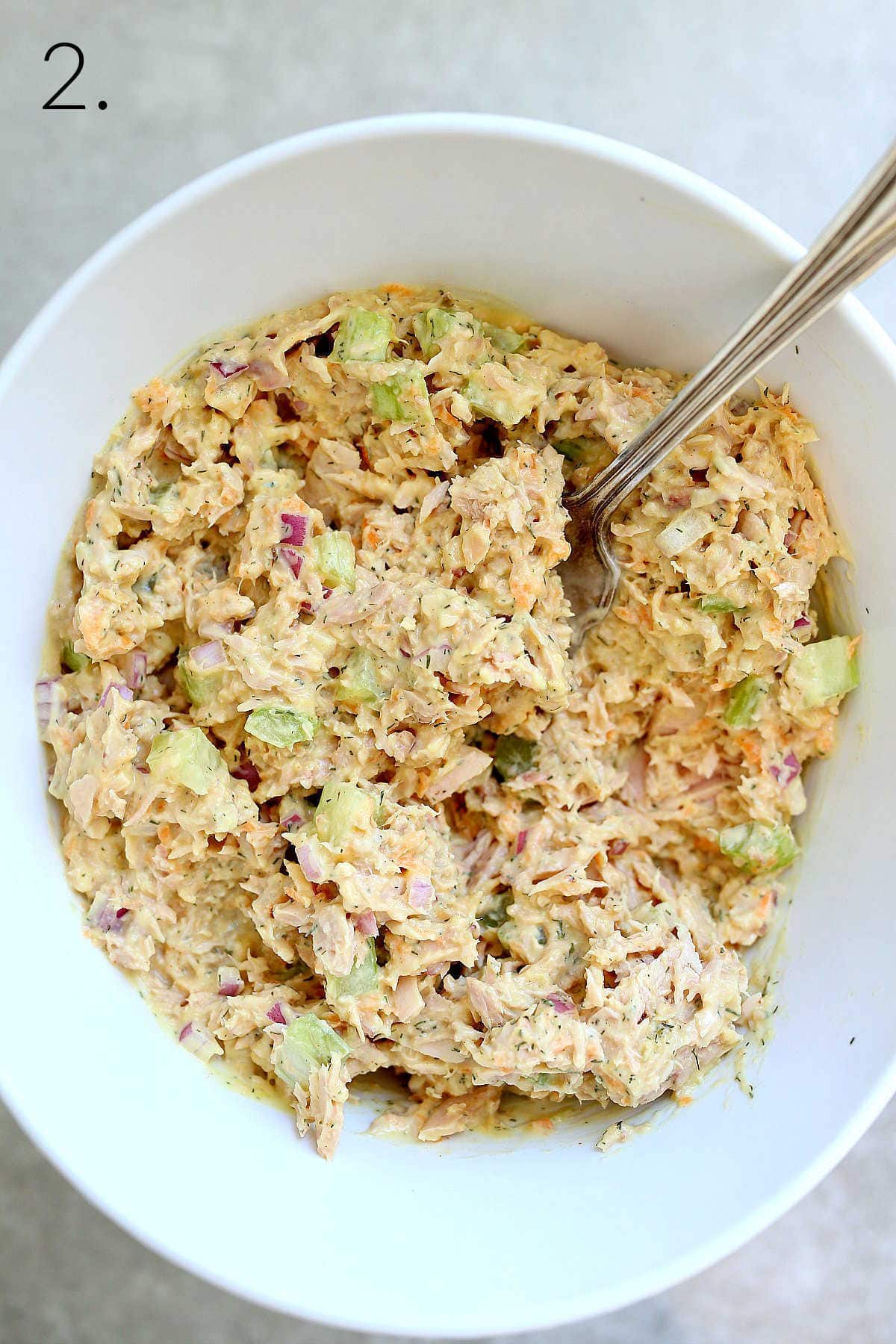 Vegan tuna in a white bowl mixed together with a serving spoon.