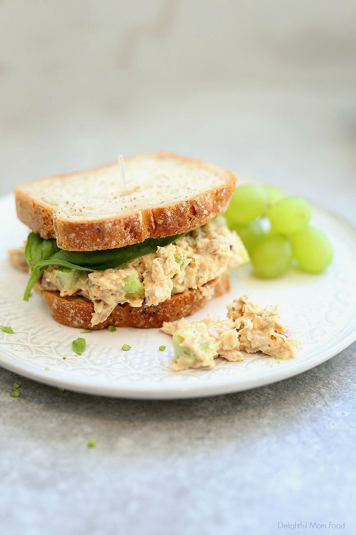 Vegan tuna sandwich on a plate with a side of green grapes.