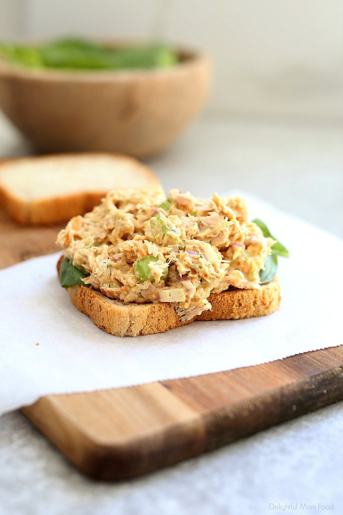 Open faced vegan chickpea salad in bread on a cutting board.