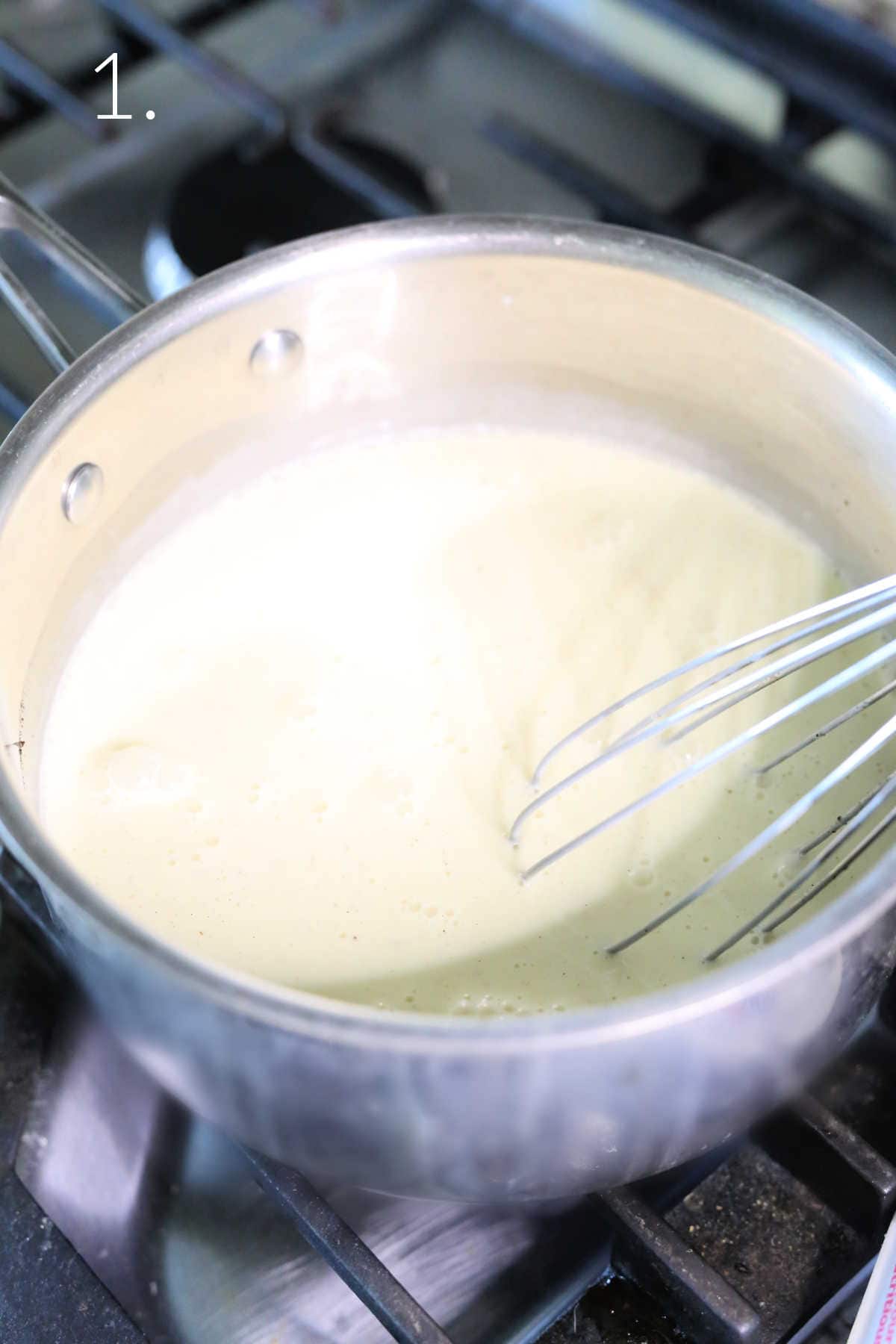 Whisking homemade ice cream with eggs in a saucepan on the stove top.