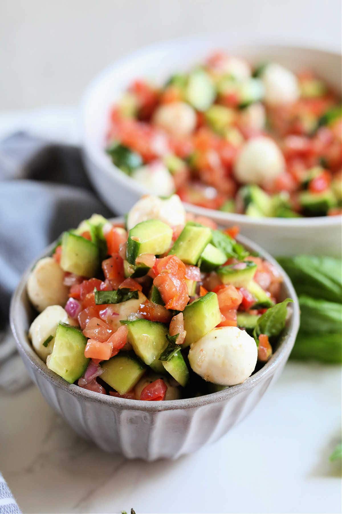 Bowl of tomato cucumber mozzarella salad with red wine vinaigrette dressing in a bowl.