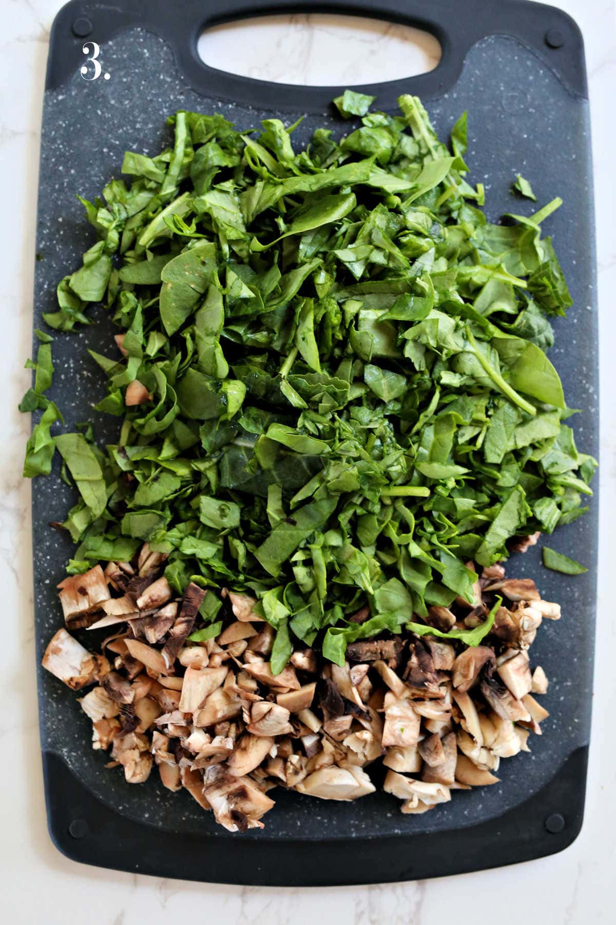 Chopped mushrooms and spinach on a cutting board.