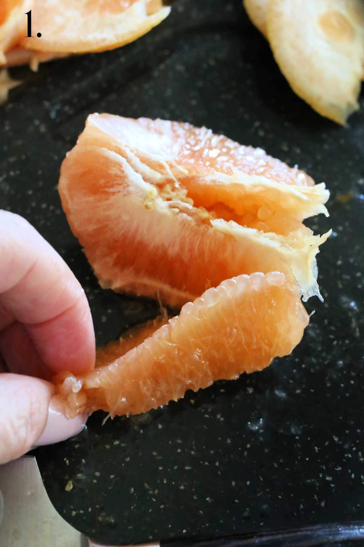 Hand removing slice of grapefruit from its membrane.