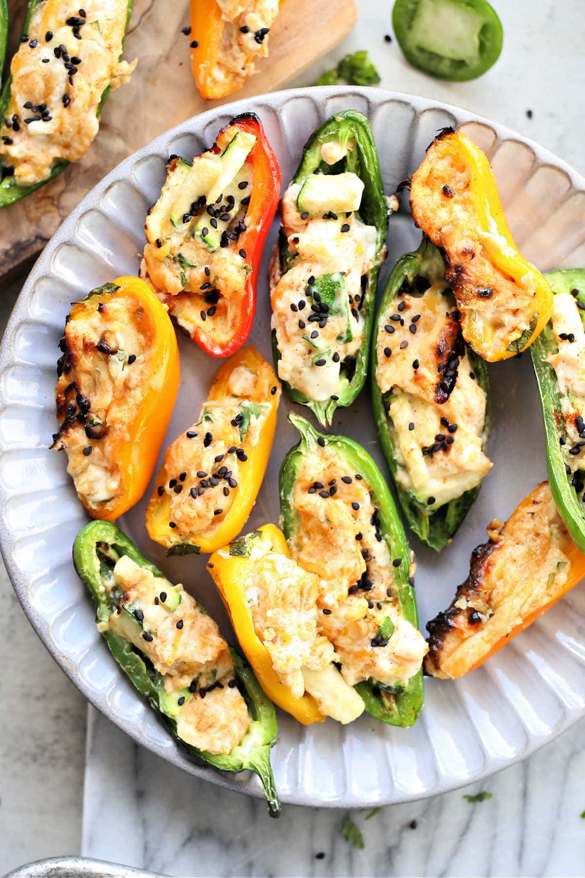 Grilled and cream cheese stuffed jalapeno peppers and sweet peppers on plate.