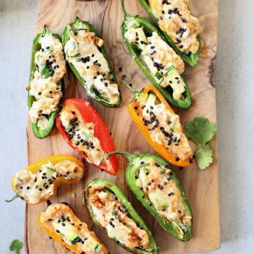 Easy grilled stuffed jalapenos and mini sweet peppers filled with cream cheese on a wood board.