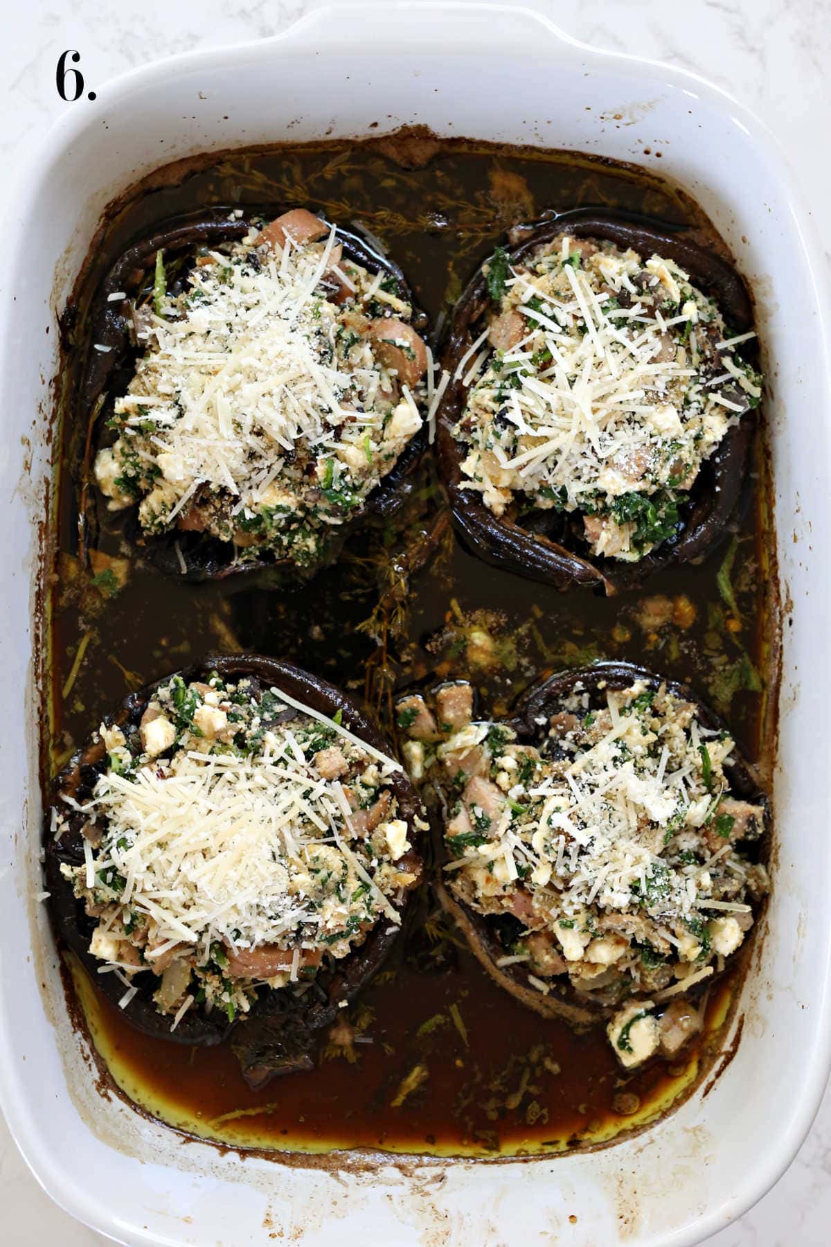 Spinach and sausage filling stuffed in portobello mushrooms in a baking dish.
