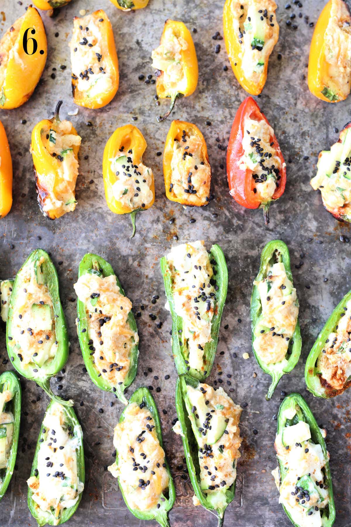 Stuffed and grilled jalapenos and mini sweet peppers filled with cream cheese filling on a baking sheet.
