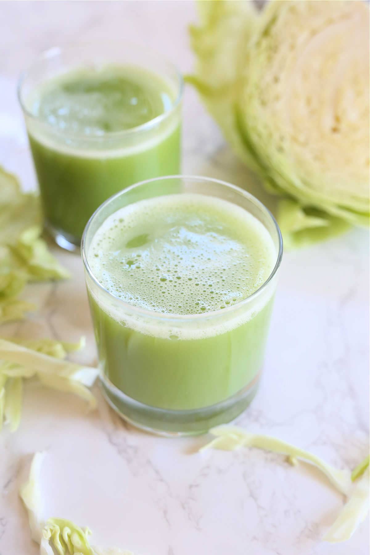 Cabbage juice recipe in a glass with raw cabbage leaves.