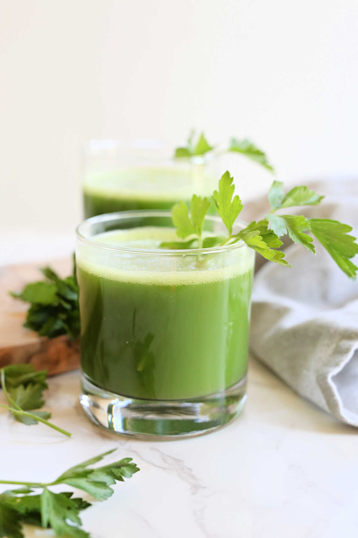 Fresh parsley juice in a glass with parsley leaves on a stem garnished in the juice.