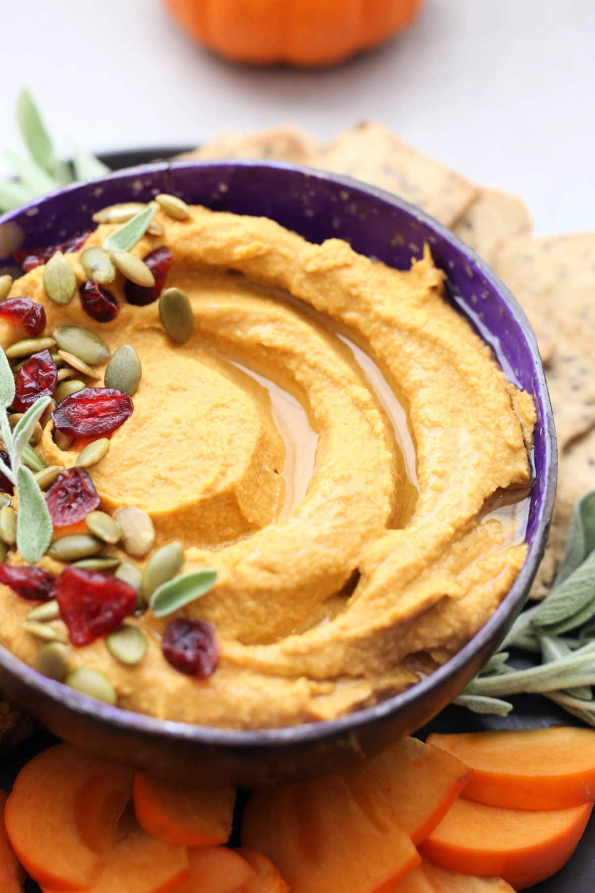 Hummus in a bowl topped with pumpkin seeds and dried cranberries.