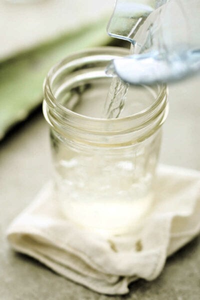 Glass of homemade aloe vera juice drink being poured from a blender.