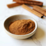 Ground cinnamon in a bowl as a substitute for cinnamon sticks.