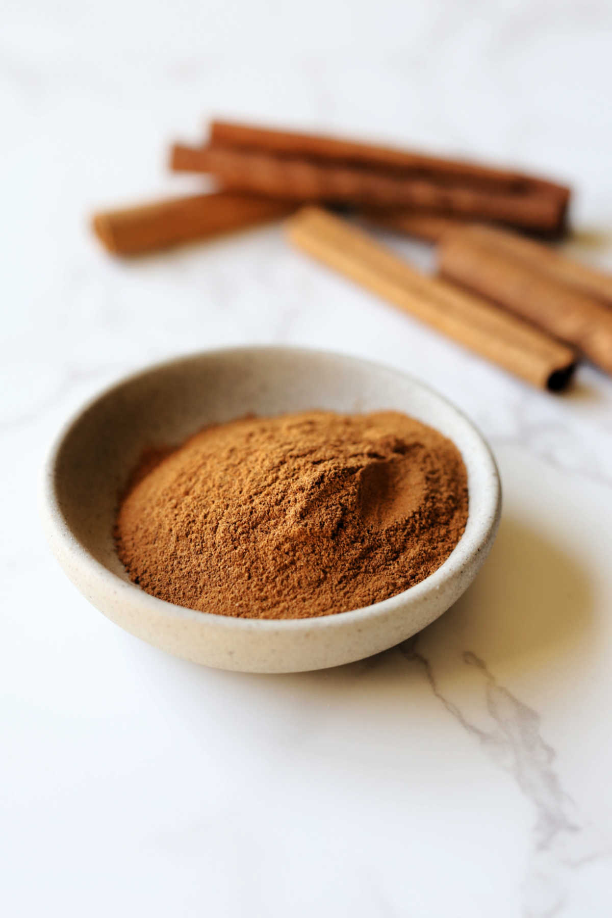 Ground cinnamon in a bowl as a substitute for cinnamon sticks.