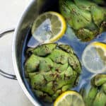 Artichoke vegetables that start with the letter A in a pot of water.