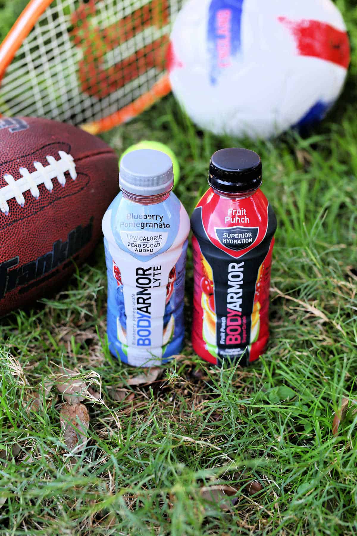 BodyArmor sports drinks in grass next to athletic gear for healthy hydration.