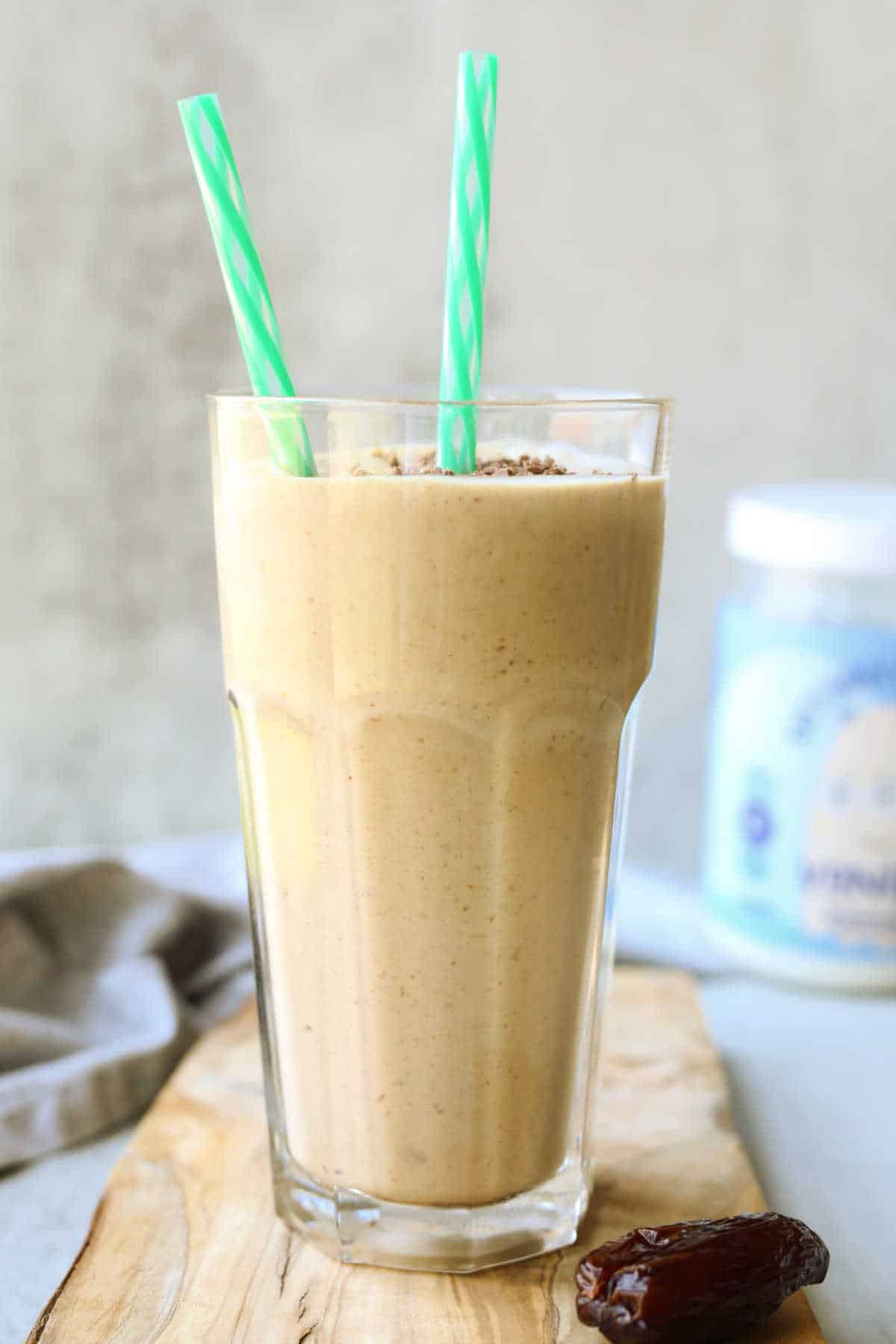 Glass of peanut butter smoothie with protein powder, bananas and dates.
