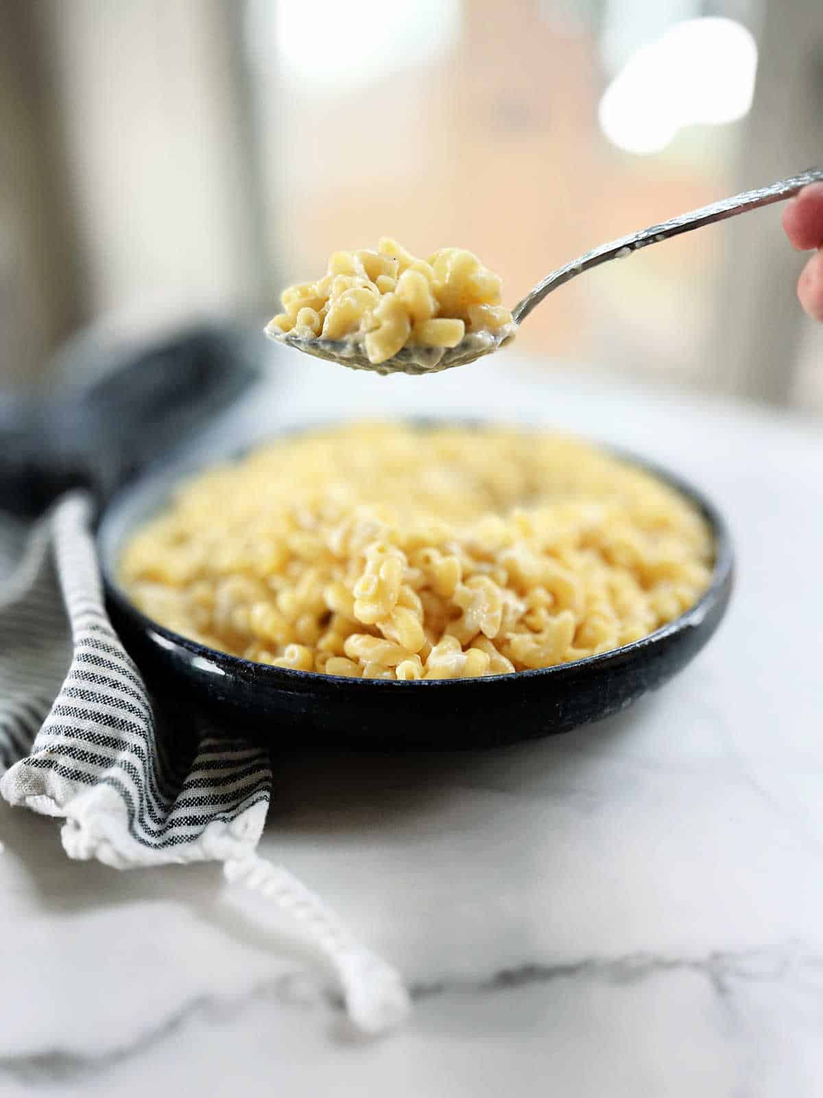 Spoon scooping homemade macaroni and cheese recipe.