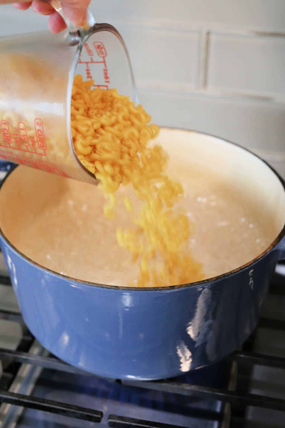 Pouring elbow pasta noodles into a pot.