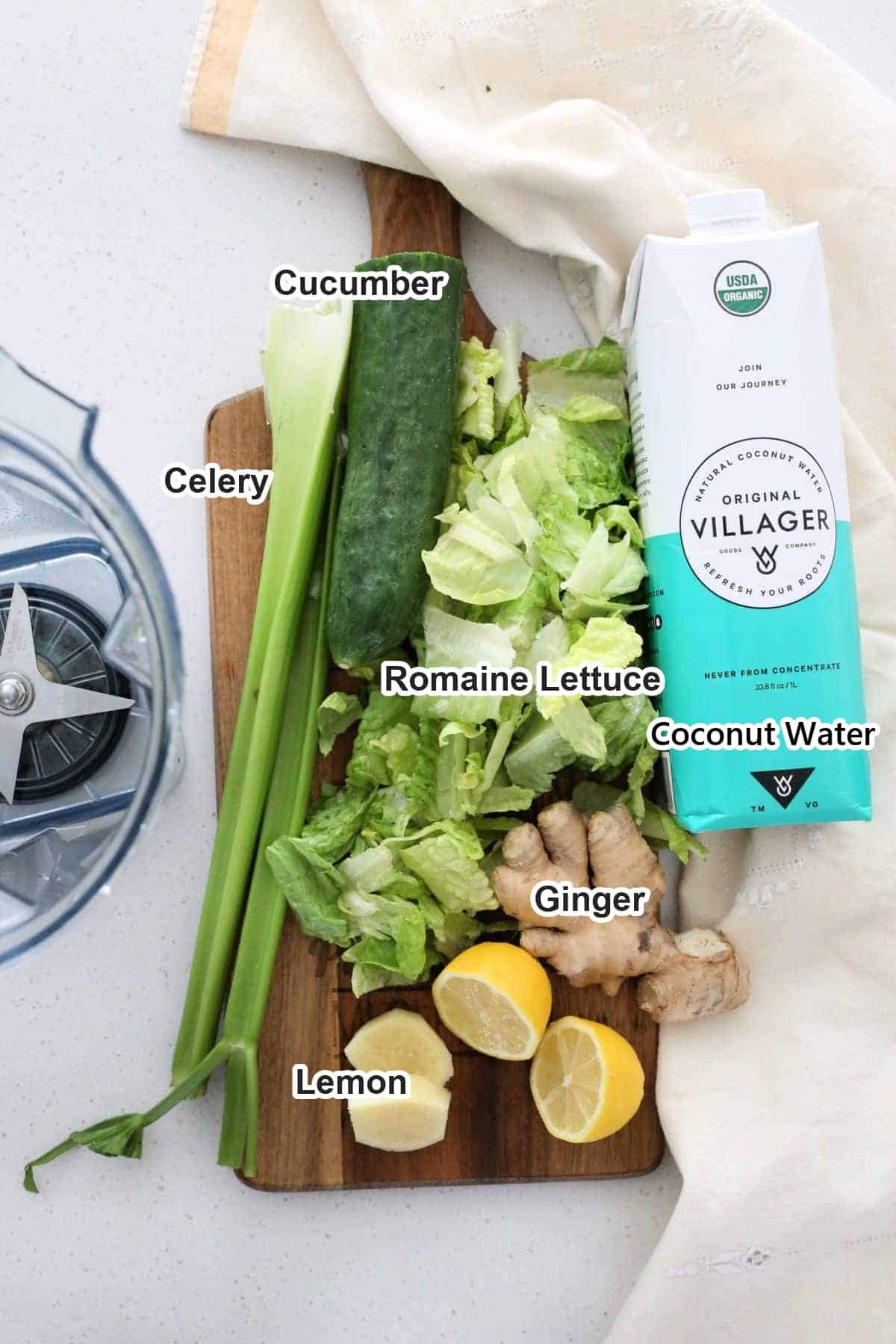 Labeled ingredients for detox green juice: cucumber, celery, romaine lettuce, coconut water, ginger and lemon on a wooden board.