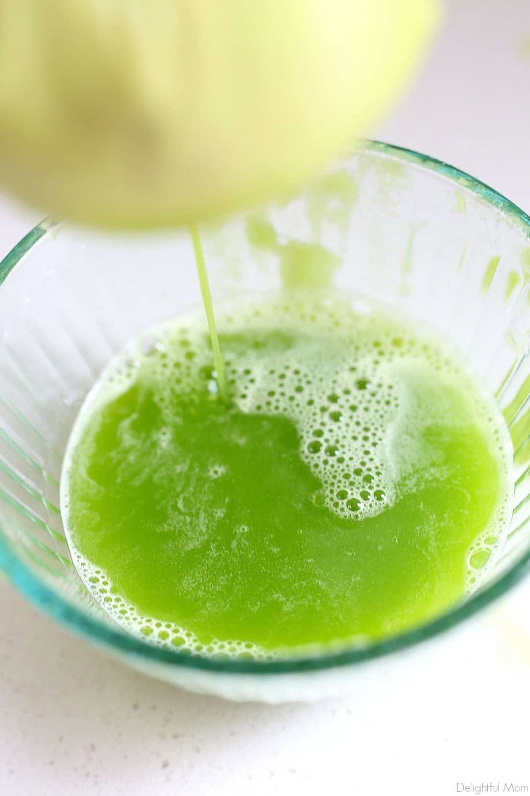 Straining blended celery juice through a nut bag into a bowl.