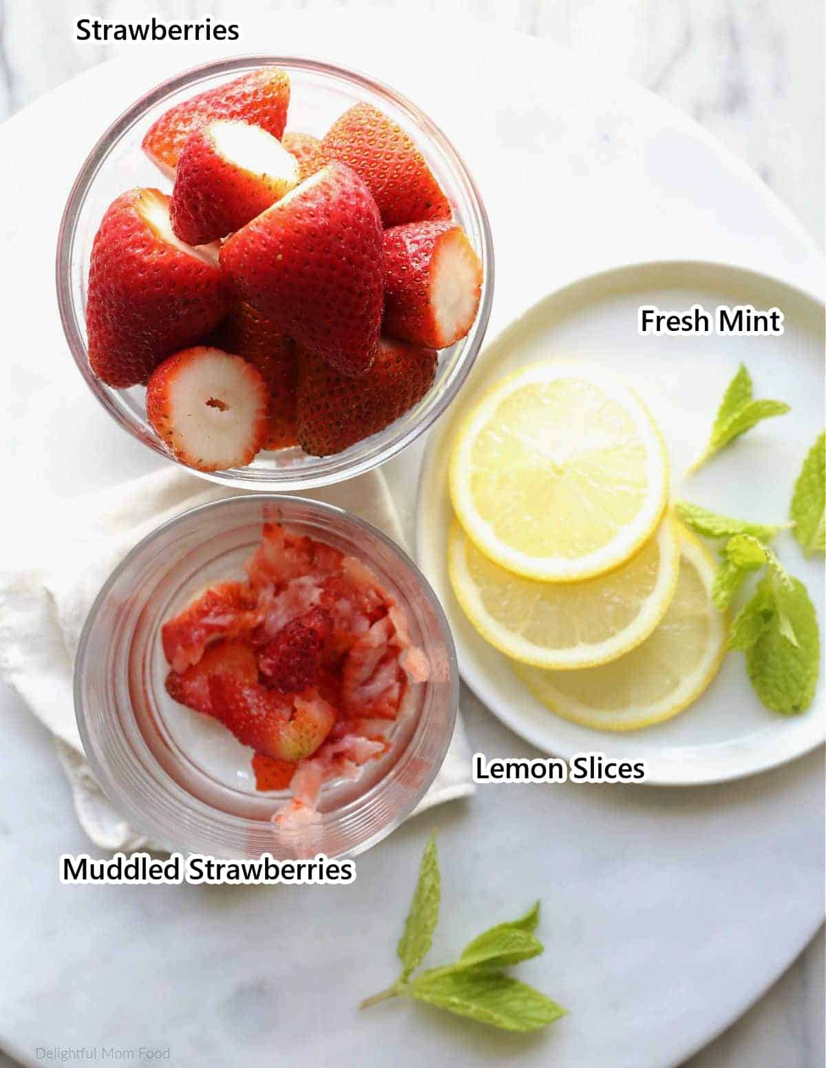 Labeled ingredients for strawberry detox water: strawberries, muddled strawberries, lemon slices and fresh mint.