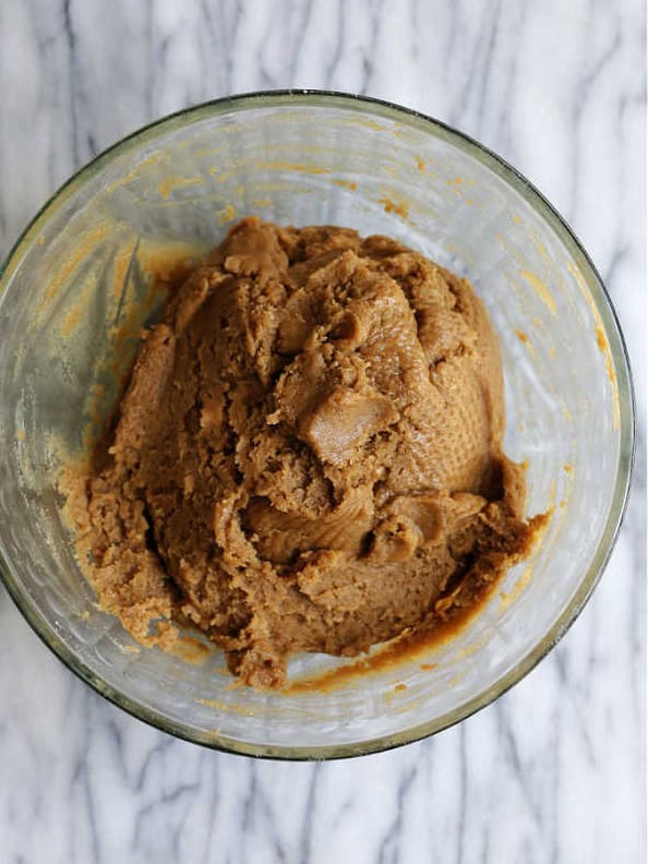 Sunbutter cookie dough formed into a ball in a glass mixing bowl after the dry ingredients are mixed in.