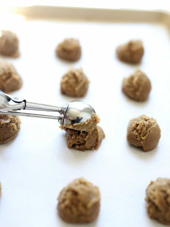 Cookie scoop portioning sunbutter cookie dough into 1-inch balls on a parchment lined baking sheet.