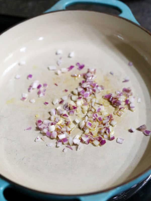 Red onions sauteing in olive oil in a large pan for taco salad filling.