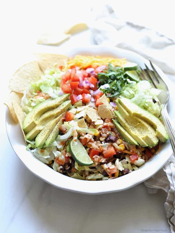 Vegetarian black bean taco salad in a serving bowl with avocado and tortilla chips.
