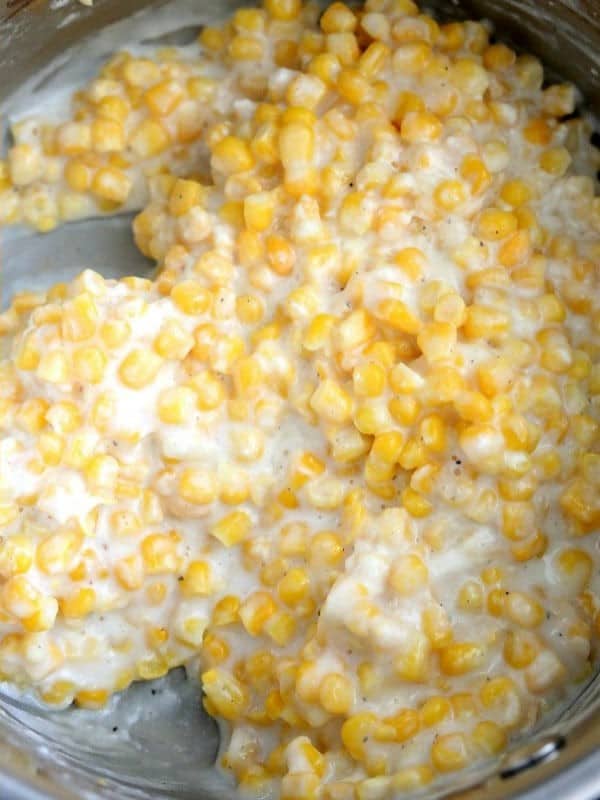 Thick, creamy cream-style corn stirred together in the saucepan.