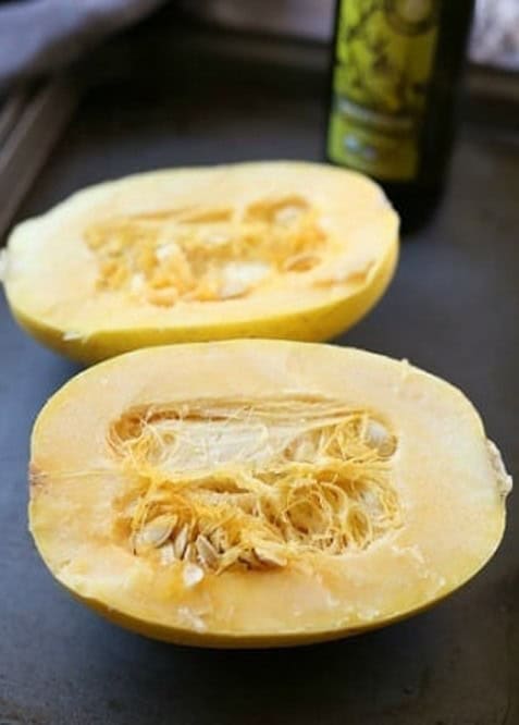 Spaghetti squash sliced in half lengthwise with the seeds still inside.