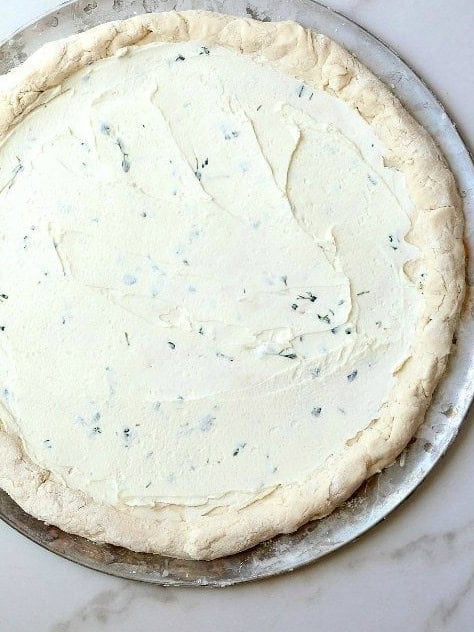 Goat cheese spread over the pizza dough.