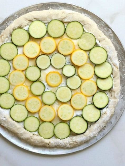 Zucchini and yellow squash slices layered in circles on the pizza.