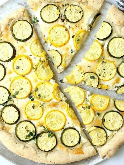 Baked zucchini goat cheese pizza sliced into pieces.